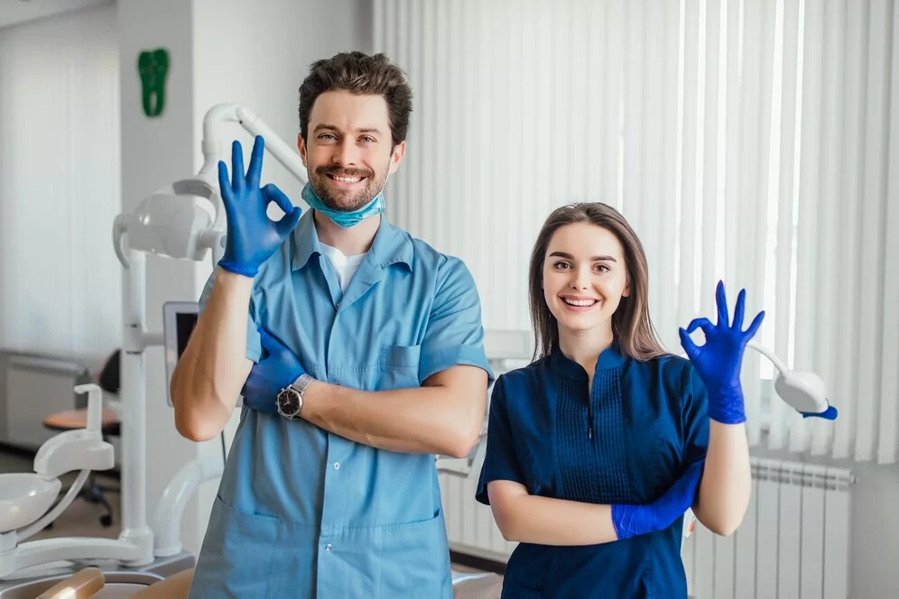 photo-smiling-dentist-standing-with-arms-crossed-with-her-colleague-showing-okay-sign_496169-1043.jpg
